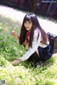 A woman sitting in a field of flowers holding a flower.