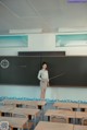 A woman standing in front of a blackboard in a classroom.