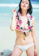 A woman in a white bikini with a flower lei around her neck.