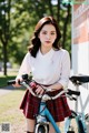 A woman in a school uniform standing next to a bike.