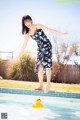 A woman in a blue dress jumping into a swimming pool.