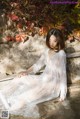 A woman in a white dress sitting on a stone ledge.