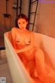 A naked woman sitting in a bathtub in a bathroom.