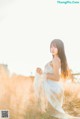 A woman in a white dress standing in a field.