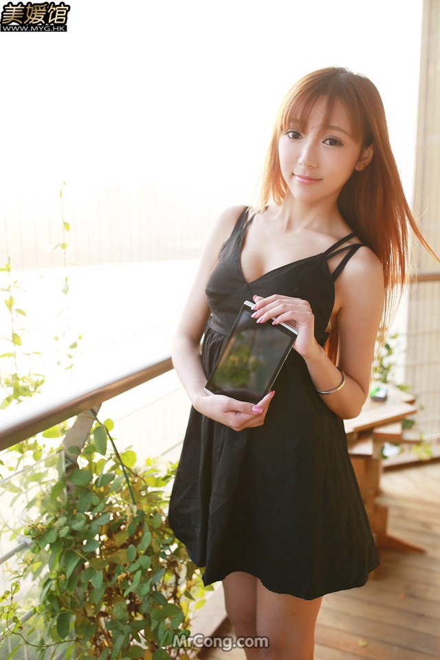 A woman in a black dress holding a tablet computer.