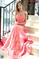 A woman in a pink dress sitting on some steps.