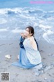 A woman sitting on a rock on the beach.