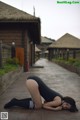 A woman in a black bodysuit laying on the ground.