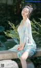 A woman sitting on a stone bench in a blue dress.